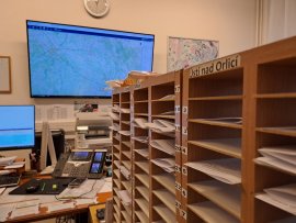 Pohled pod ruce dispečerům. Stovky papírků vystřídaly tabulky v počítači.